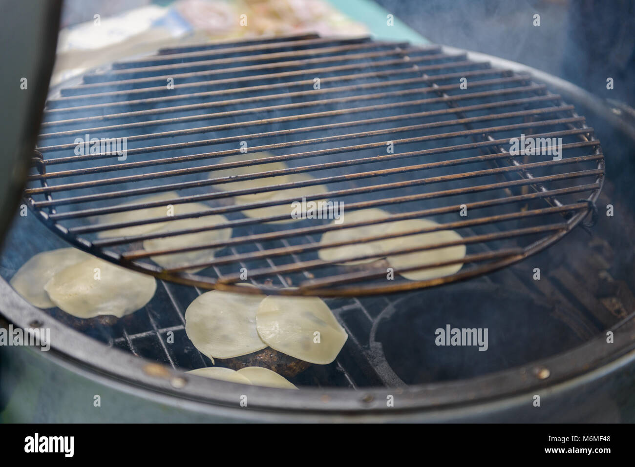 Chef making beef burgers outdoor on open kitchen international food festival event. Street food ready to serve on a food stall. Stock Photo