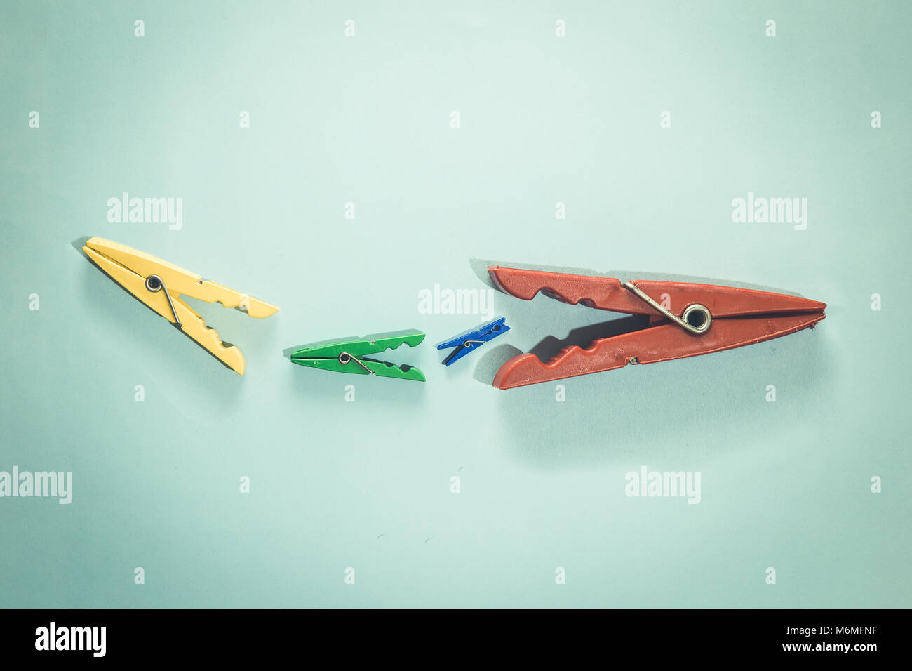 Clothespins devour each other. Food chain minimal concept. Stock Photo