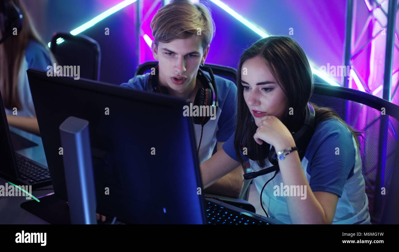 Boy and Girl Gamers Actively Thinking/ Discussing Game Strategy/ Tactic, They're In Internet Cafe or on Cyber Games Tournament. Stock Photo