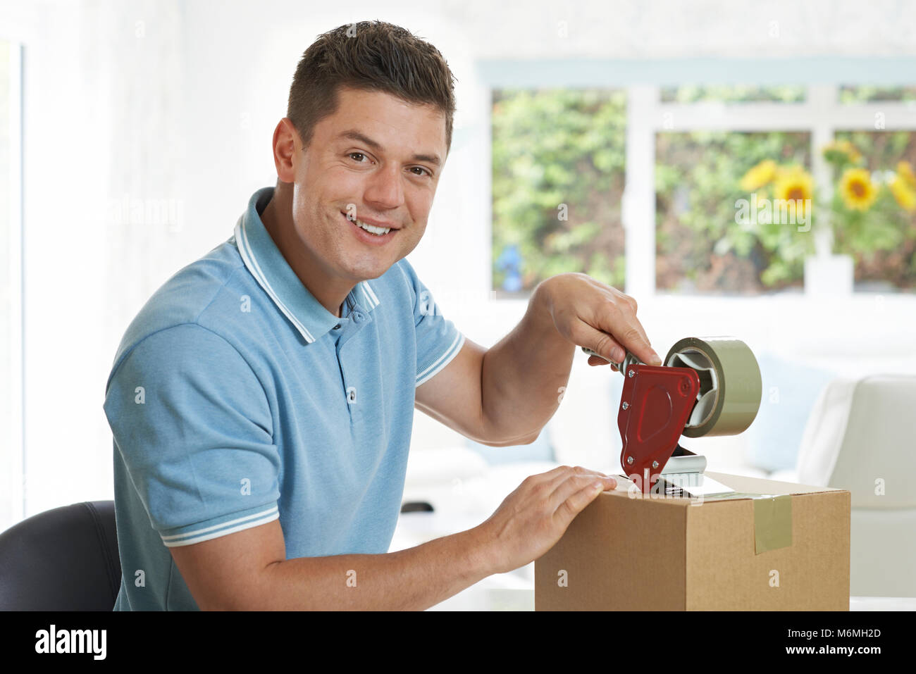 Portrait Of Man At Home Sealing Box For Dispatch Stock Photo