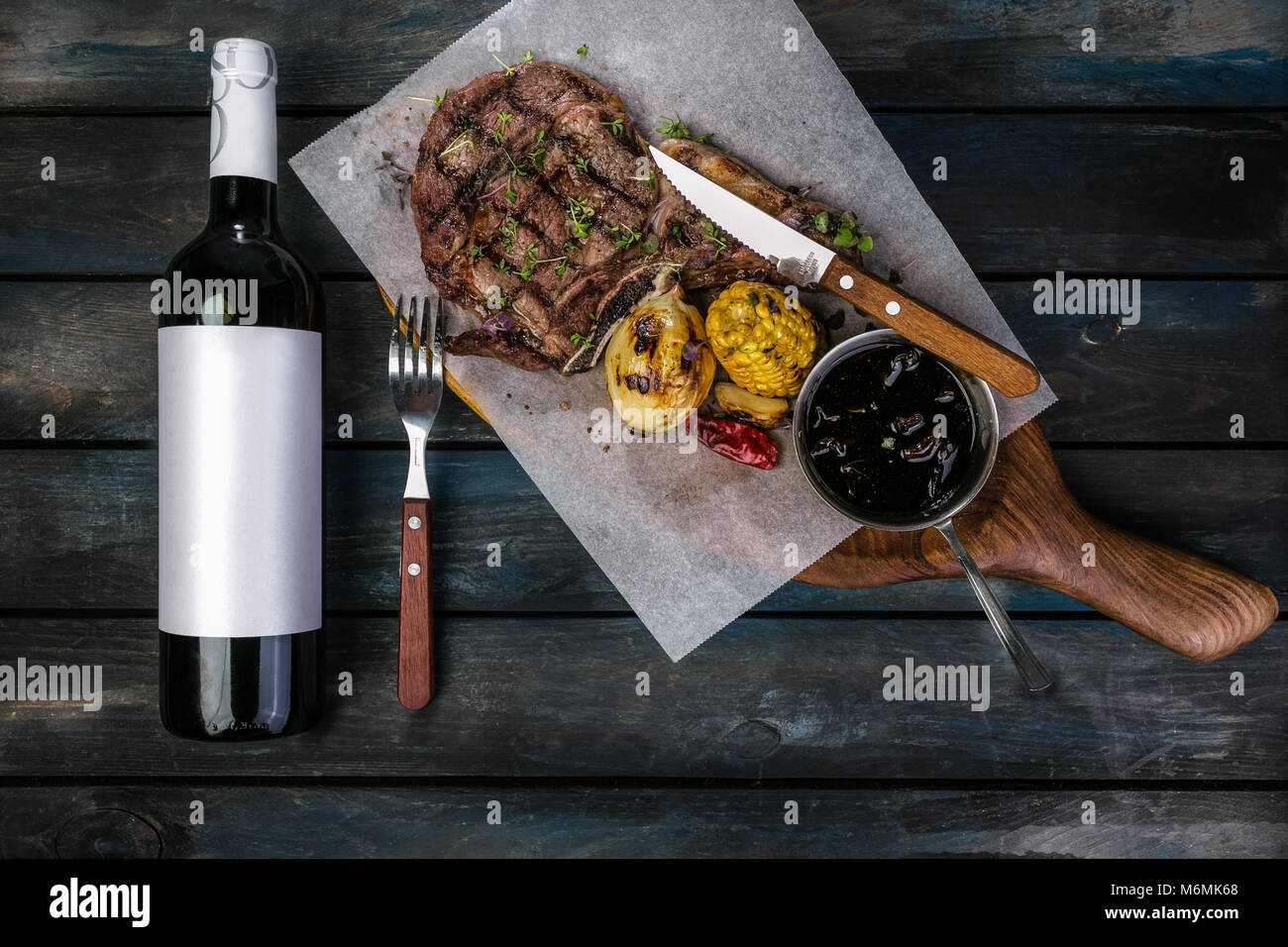 Rib eye steak on cooking paper or parchment on wooden desk with ...