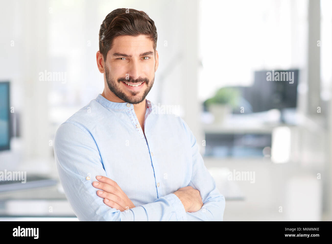 Portrait of a young businessman standing with arms crossed at the ...