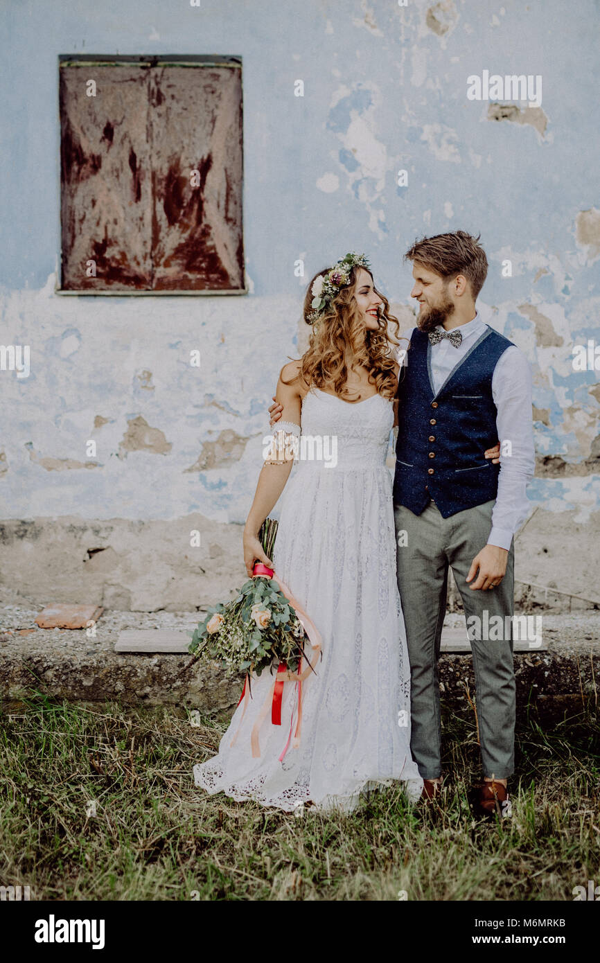 Beautiful bride and groom in front of old shabby house Stock Photo - Alamy