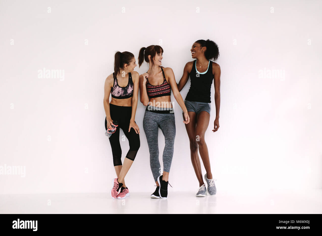 Group of young sporty girls talking. Women chatting while having a break in fitness studio. Stock Photo