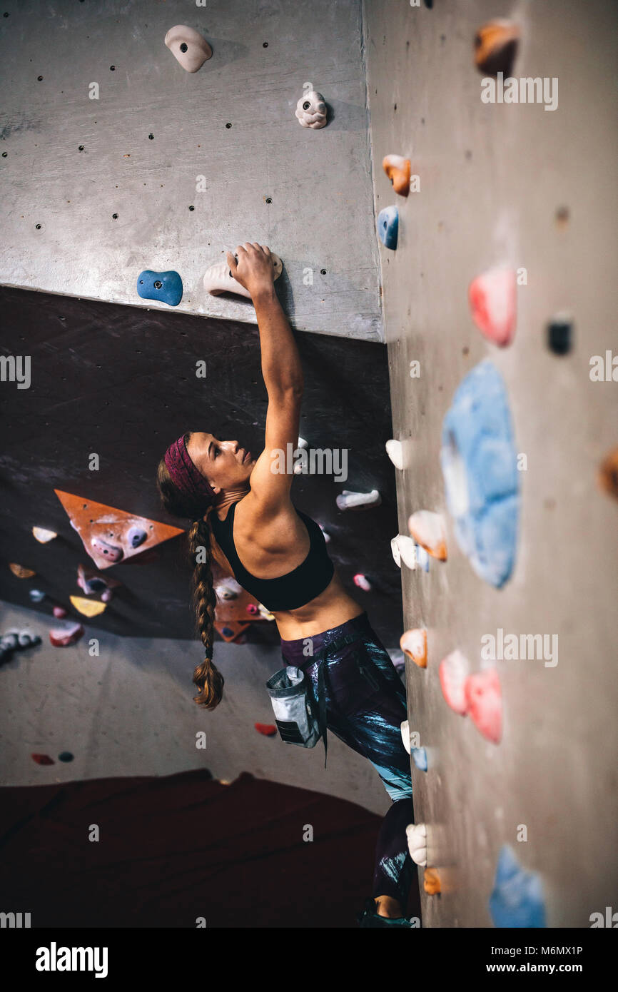 Woman bouldering at an indoor climbing centre. Climber practicing rock