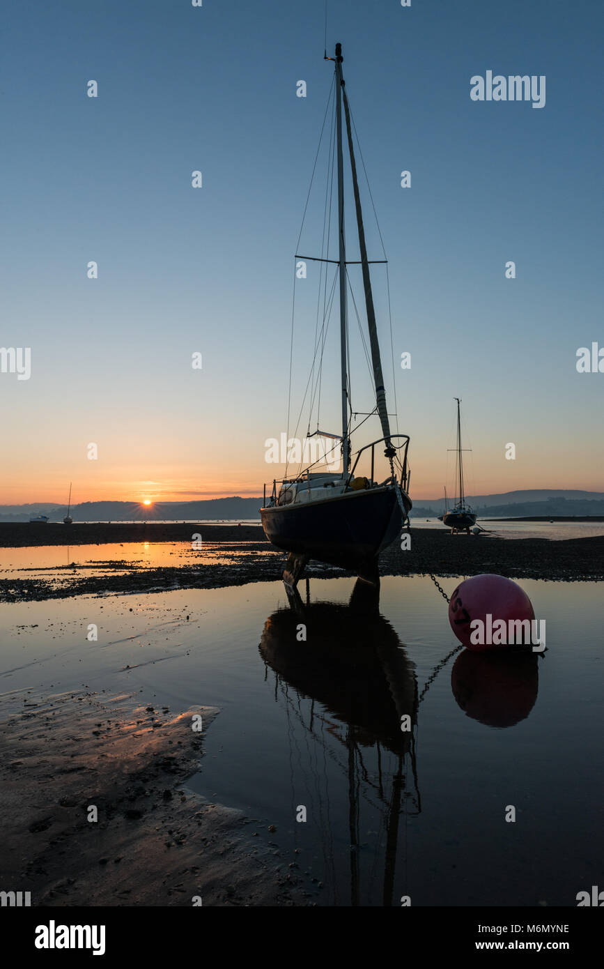 Sunset at shelly beach at the Exe estuary with boats and reflections Stock Photo