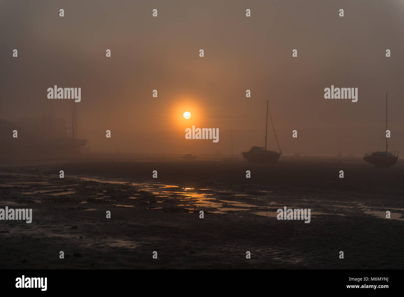 Misty sunset at shelly beach at the Exe estuary with boats Stock Photo