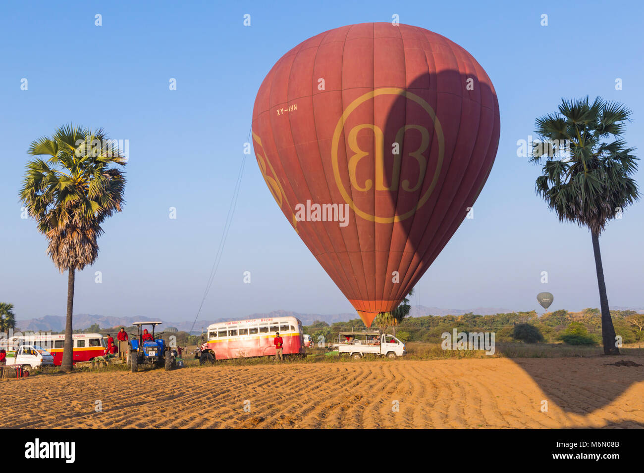 Balloons over Bagan buses and crew wait for hot air balloons to land at Bagan at dawn, Myanmar (Burma), Asia in February Stock Photo