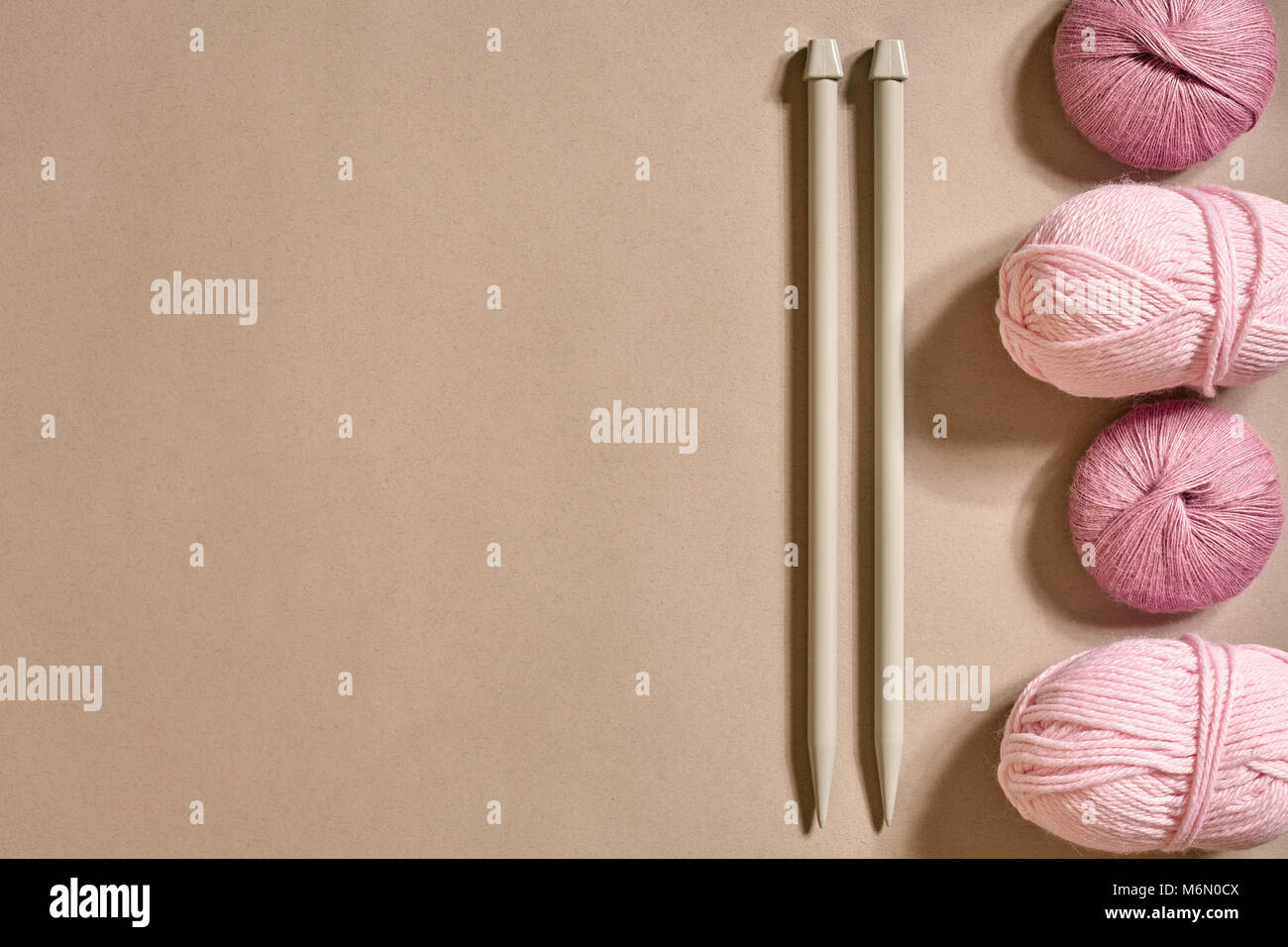 A group of colored balls of yarn and knitting needles on a beige