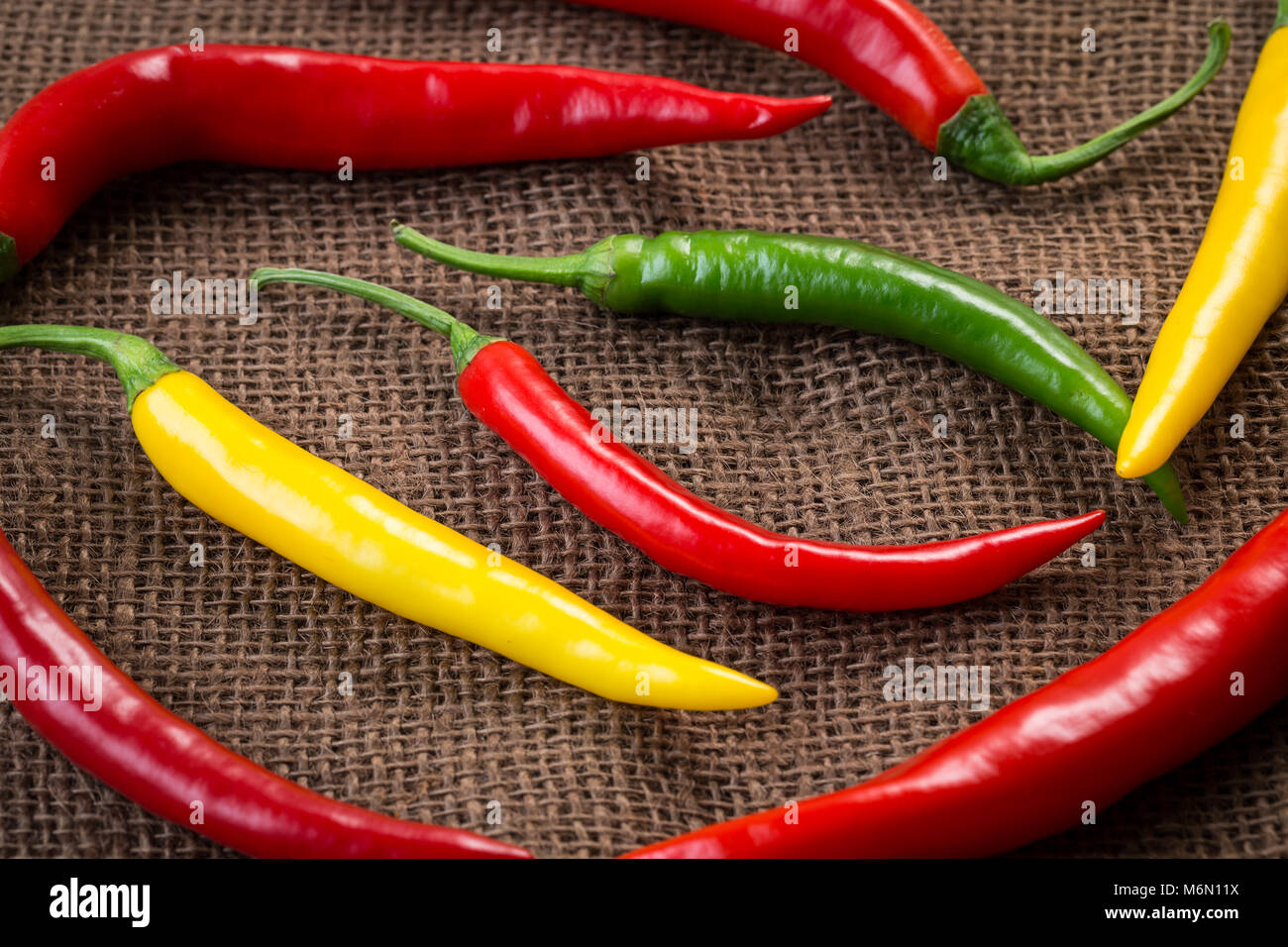 Fresh chili peppers - yellow, green and red chili pepper on brown ...