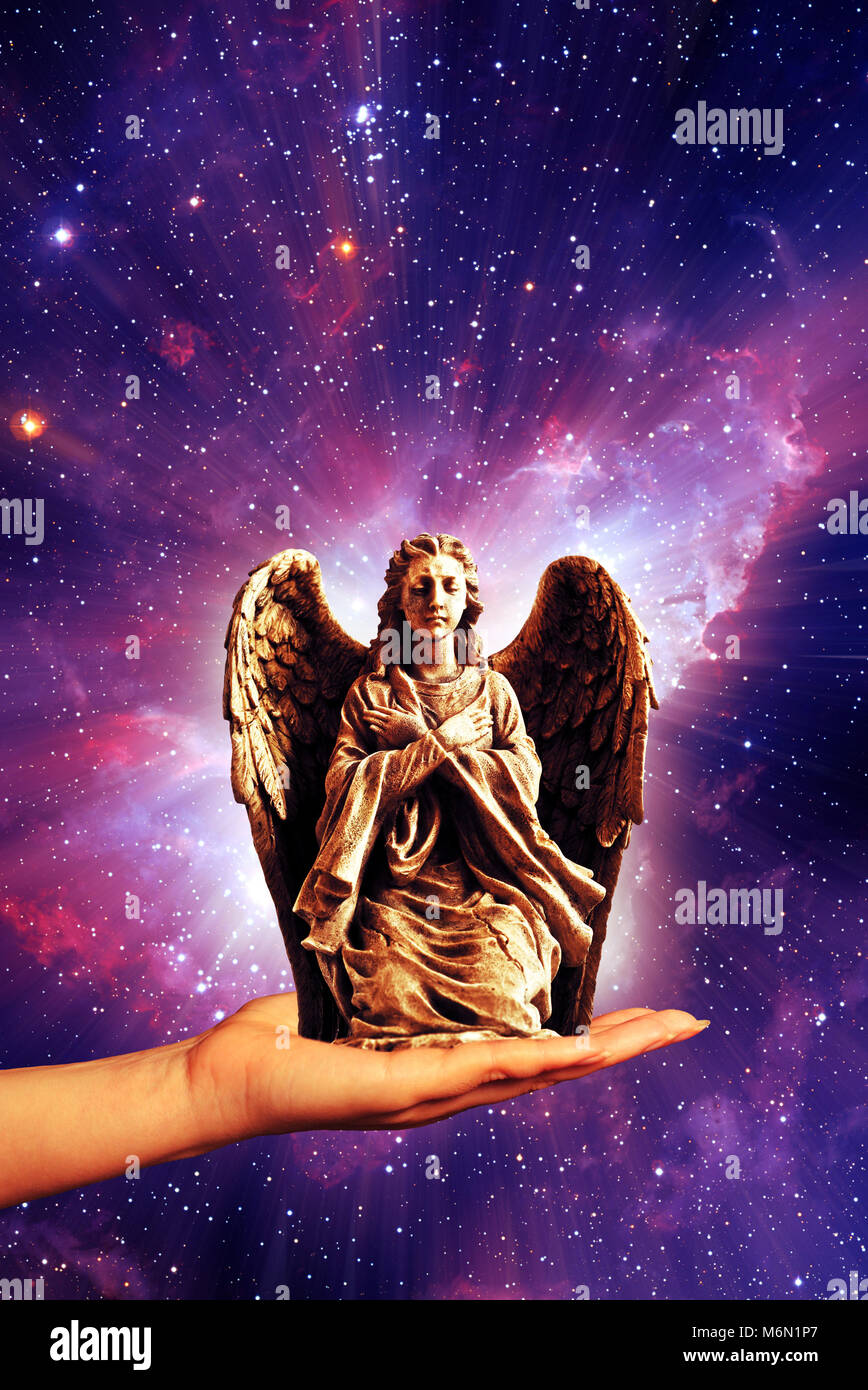 hand holding an angel statue with divine light Stock Photo Alamy