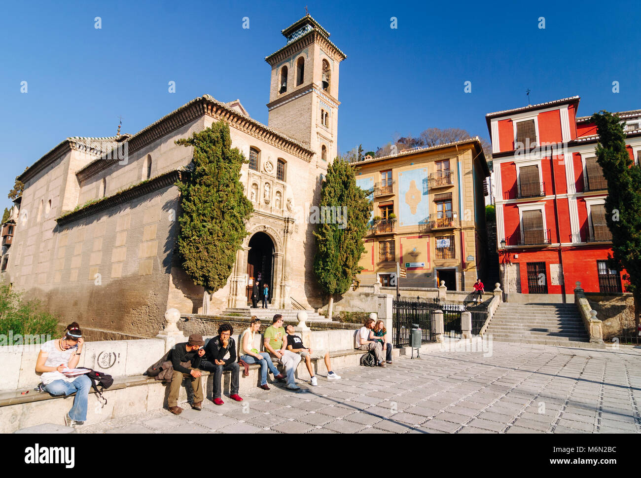 Granada, Andalusia, Spain. Tourists and young locals alike sit by the Santa Ana church in Plaza Nueva sq. in the Unesco listed Albaicin district . Stock Photo