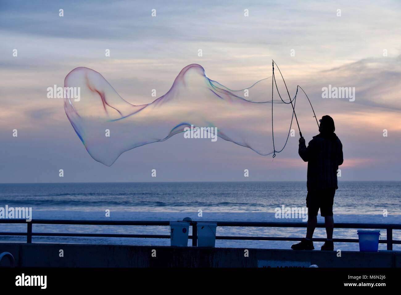 Male performer making large, big soap bubbles at sunset overlooking