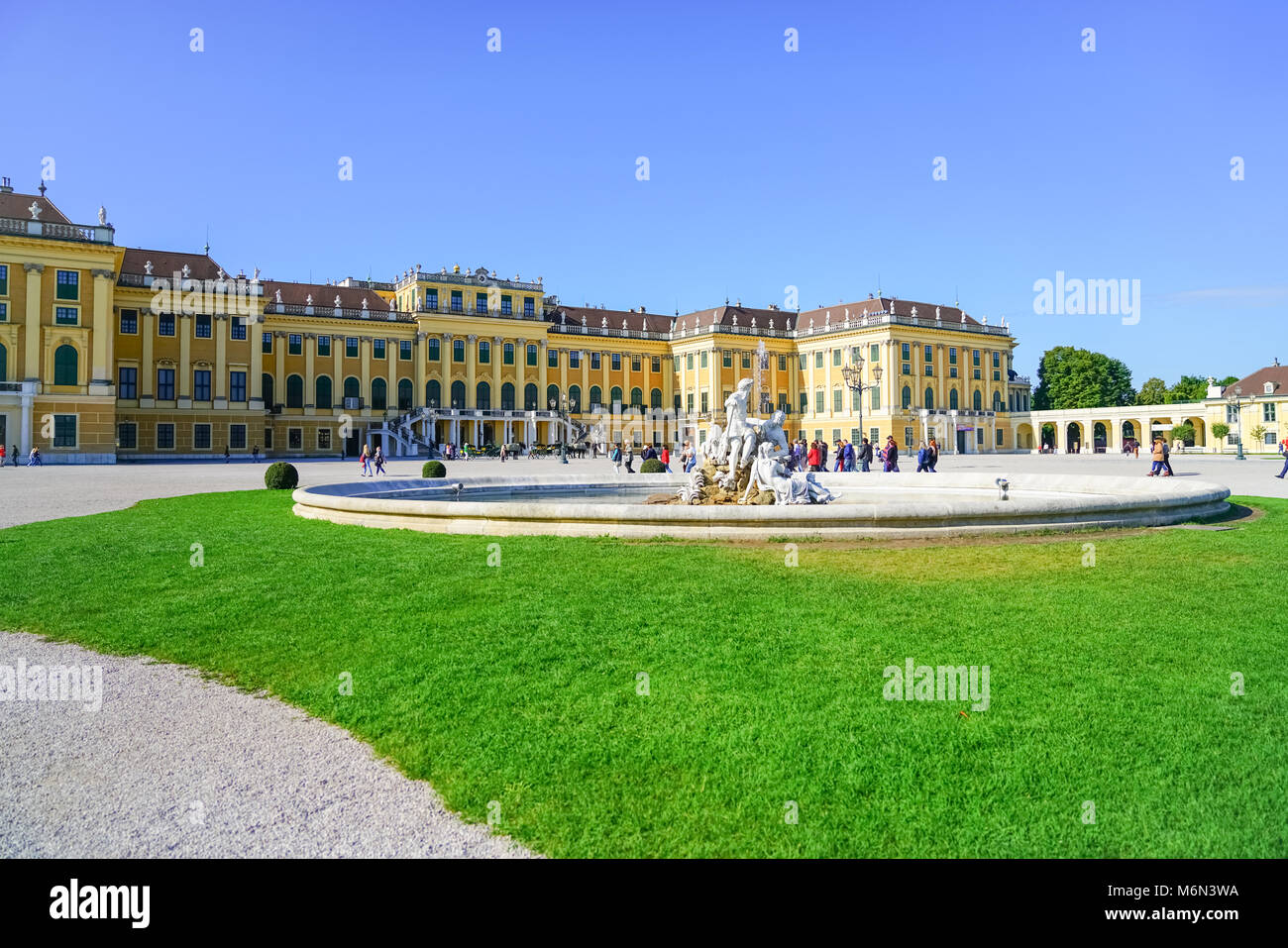 VIENNA,AUSTRIA - SEPTEMBER 4 2017; Tourists arriving ai morning walking past lawn and fountain in front baroque architectural detail of the Schonbrunn Stock Photo