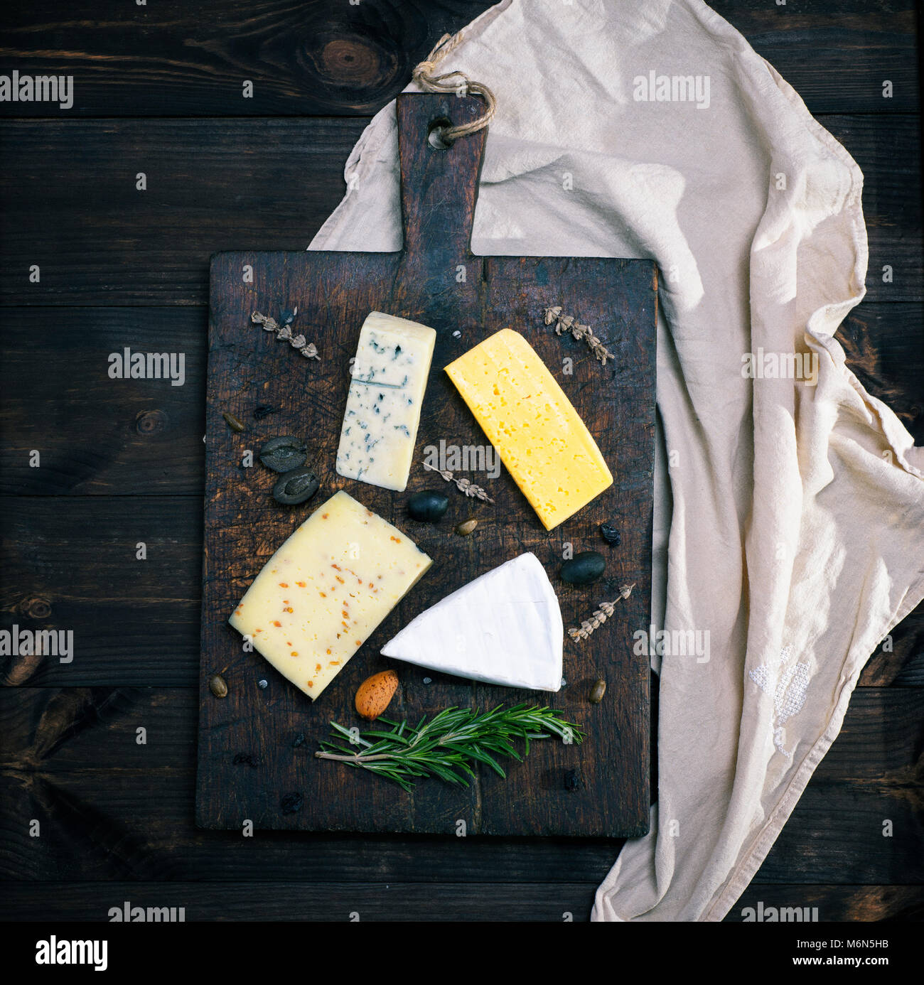 pieces of different cheeses on a brown wooden board brie, roquefort