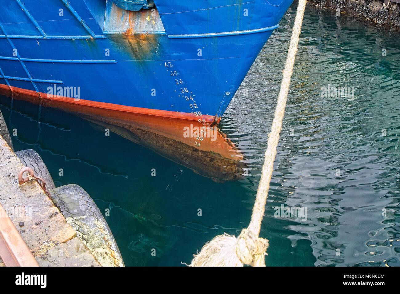 Ship in the harbor. Water. Red bow nose. Blue hull. Anchor. Draft scale numbers Stock Photo