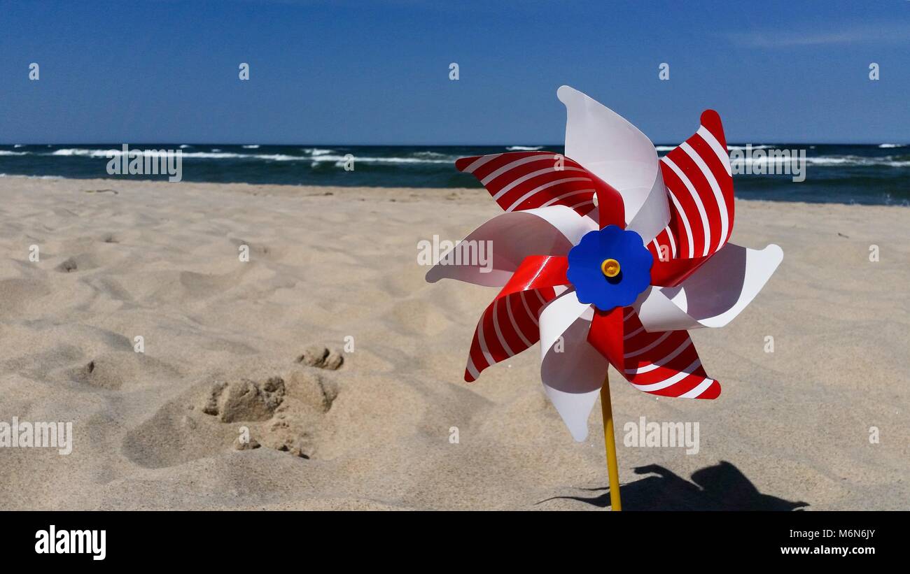 Red / white / blue / yellow - fan on the sunny sandy beach. Stock Photo