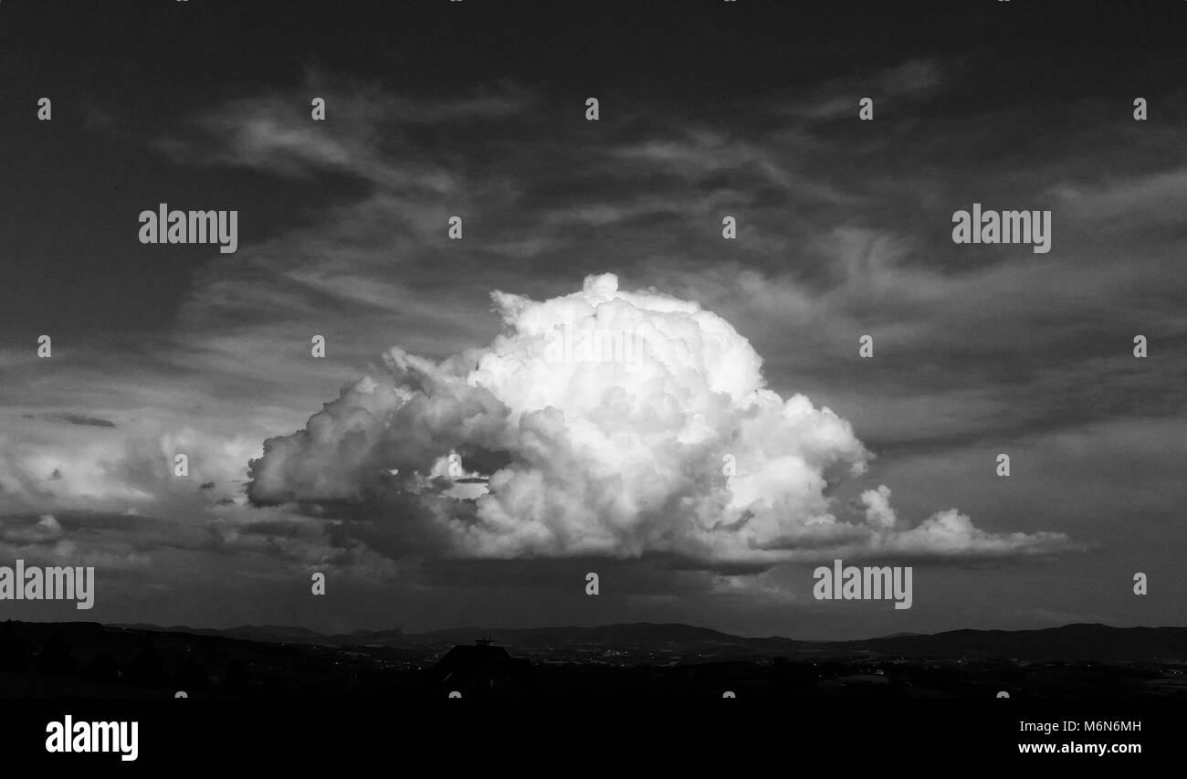 Storm cloud over the countryside. Cloud illuminated by sun. Black and white version. Stock Photo