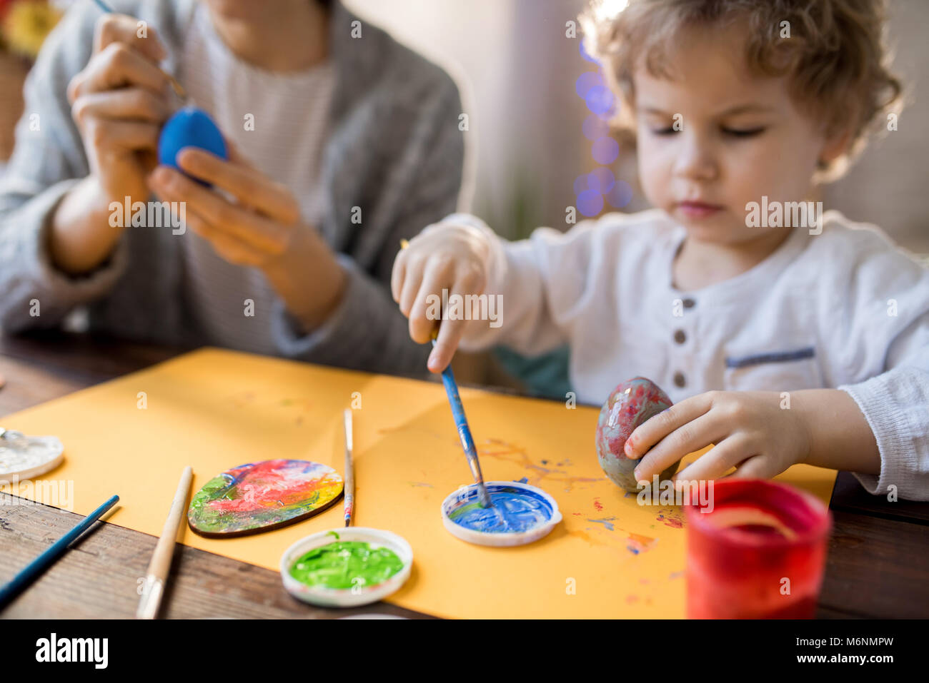 Cute Toddler Painting Easter Eggs with Mom Stock Photo