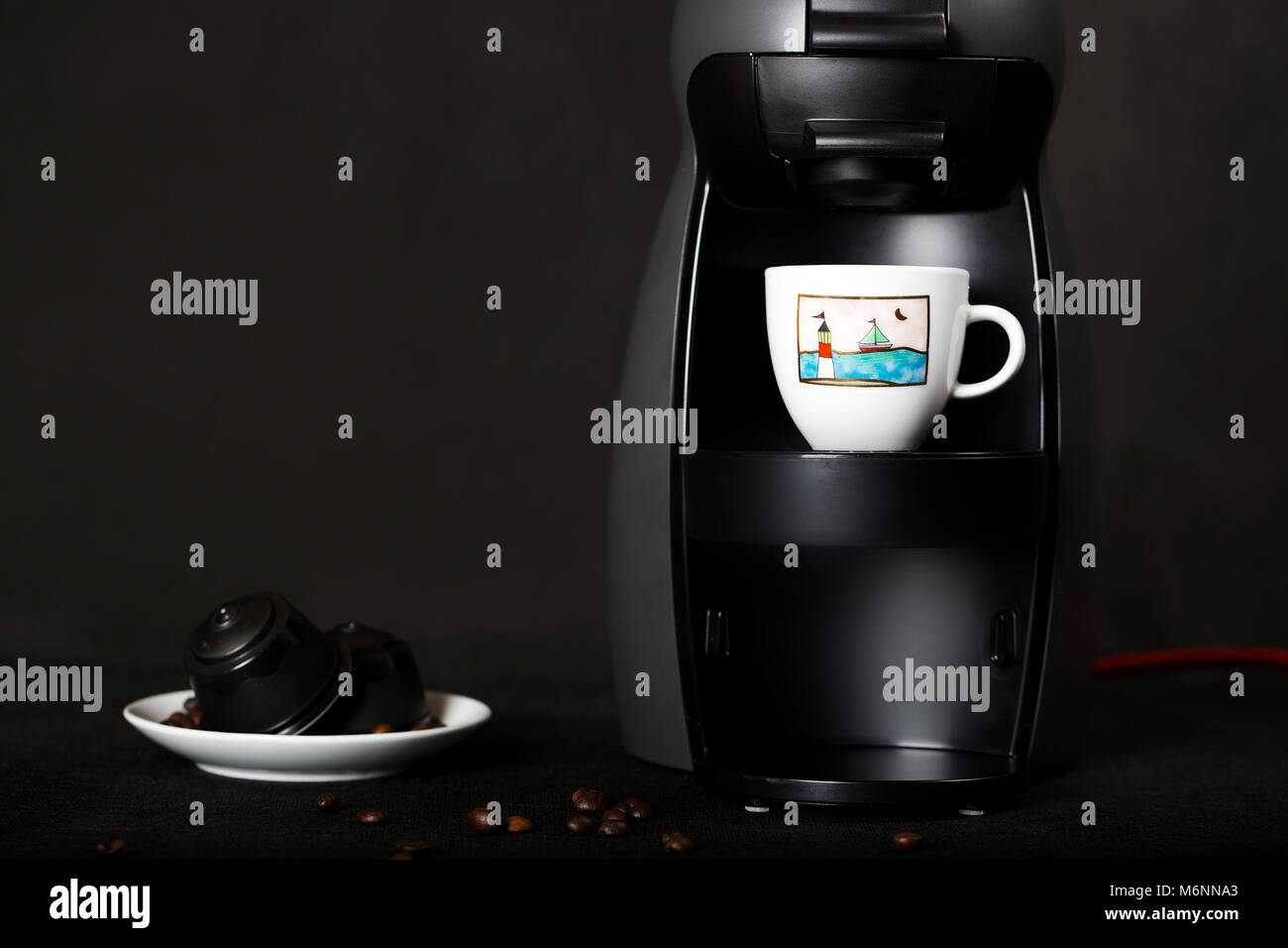 Black coffeemaker and coffee capsules n a black background. Closeup Stock Photo