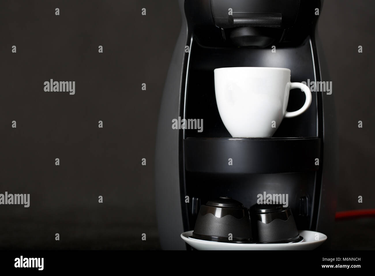 Black coffeemaker and coffee capsules n a black background. Closeup Stock Photo