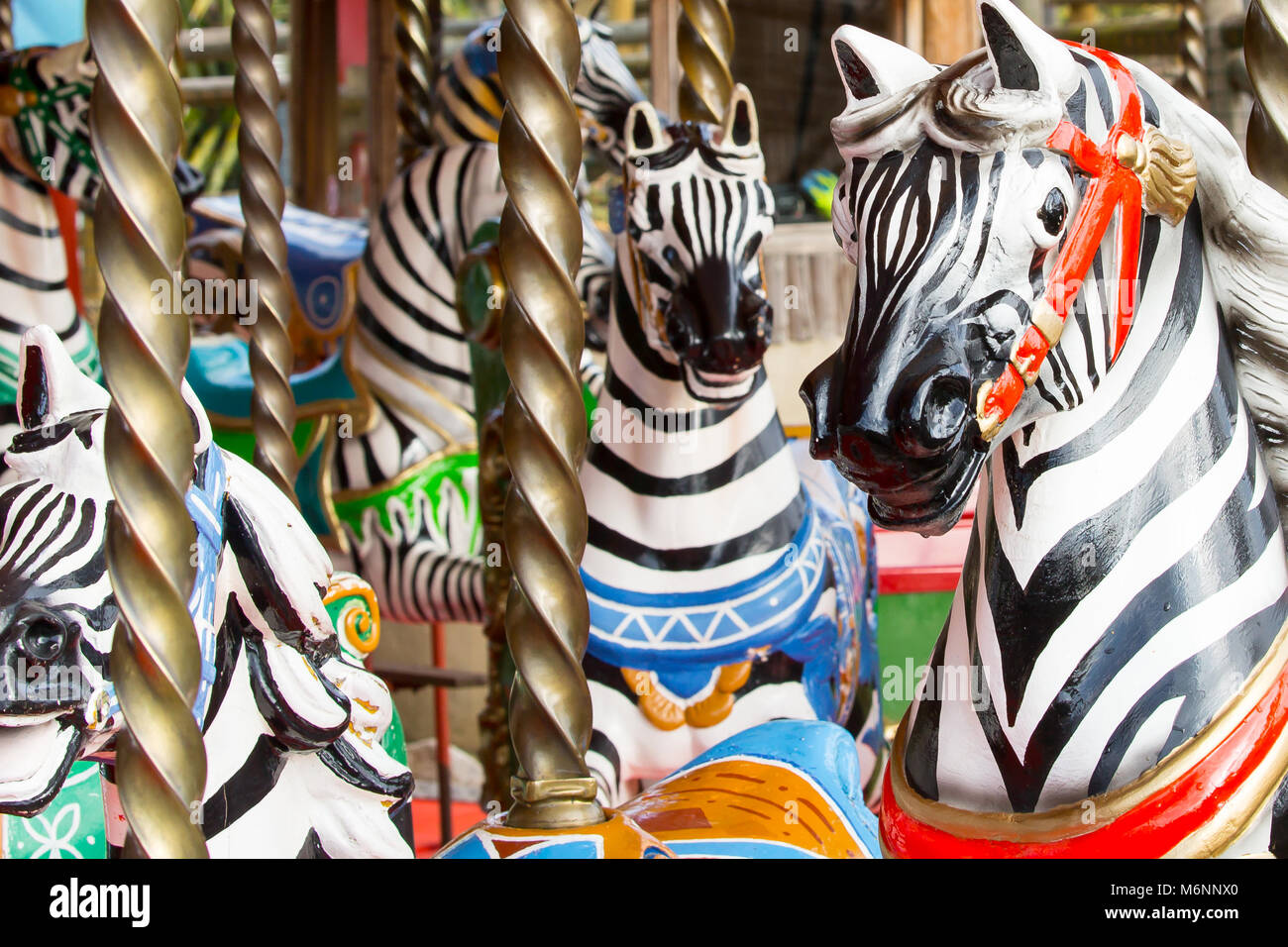 Close up of brightly painted, colourful zebras on a traditional British fairground carousel ride. UK merry-go-round, amusement ride. Stock Photo