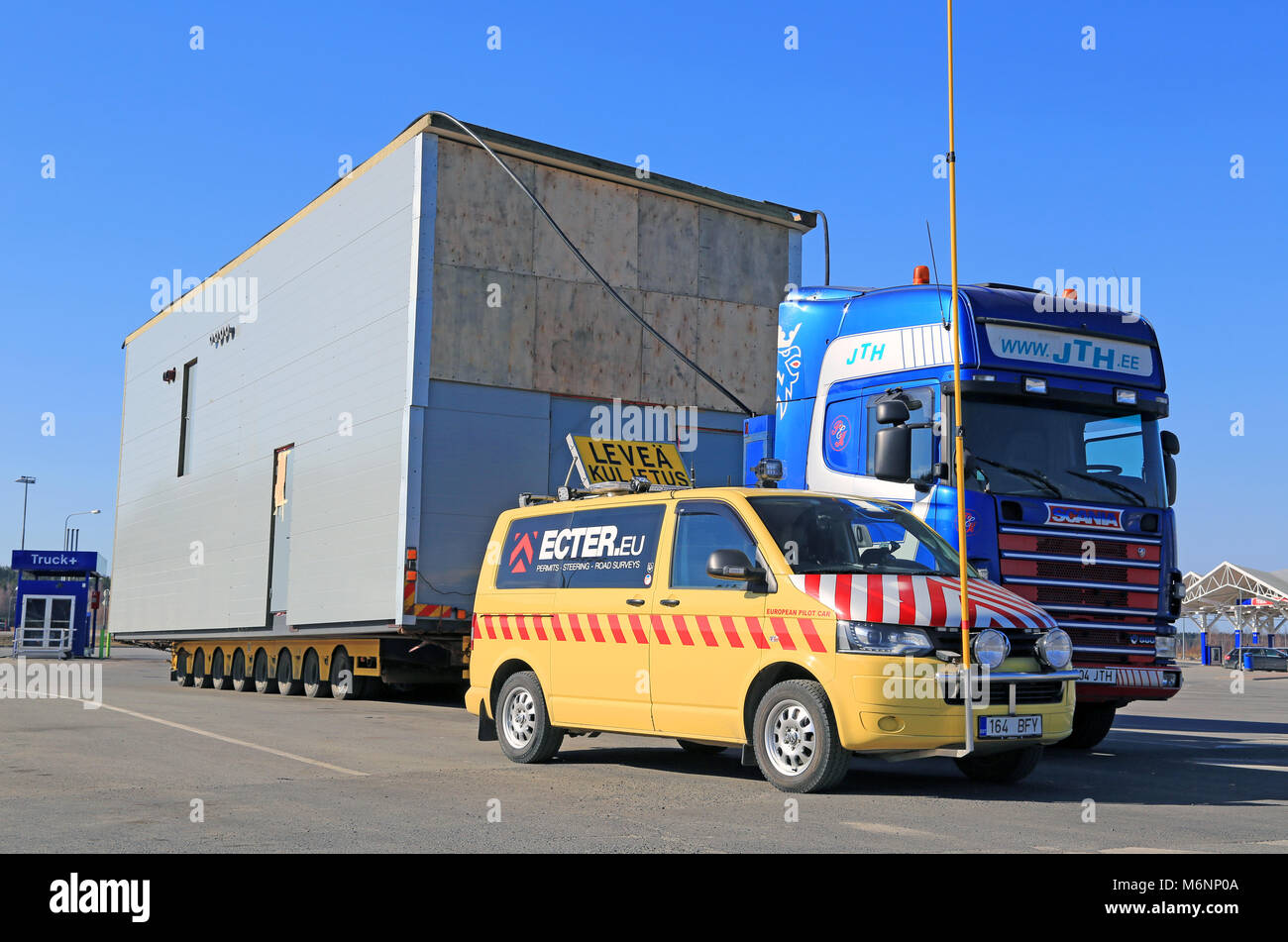 FORSSA, FINLAND - MARCH 29, 2014: Pilot car and a heating plant as an oversize load. On Finnish roads an escort car is necessary, if the load exceeds  Stock Photo