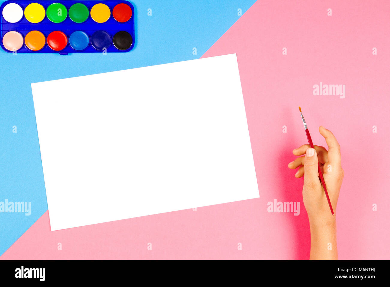 Child hand painting with paintbrush and watercolor paints on colorful background Stock Photo