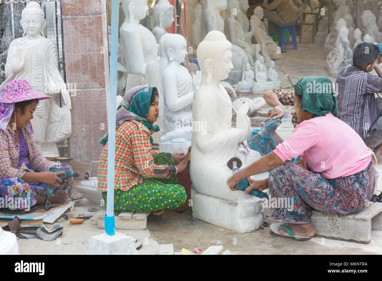Local women sculpting marble Buddha, Amarapura Mandalay, Myanmar (Burma), Asia in February - working at marble stone carving workshops covered in dust Stock Photo