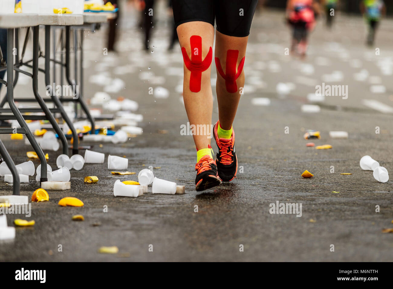 legs female runner red kinesio tape on knees run next to water point