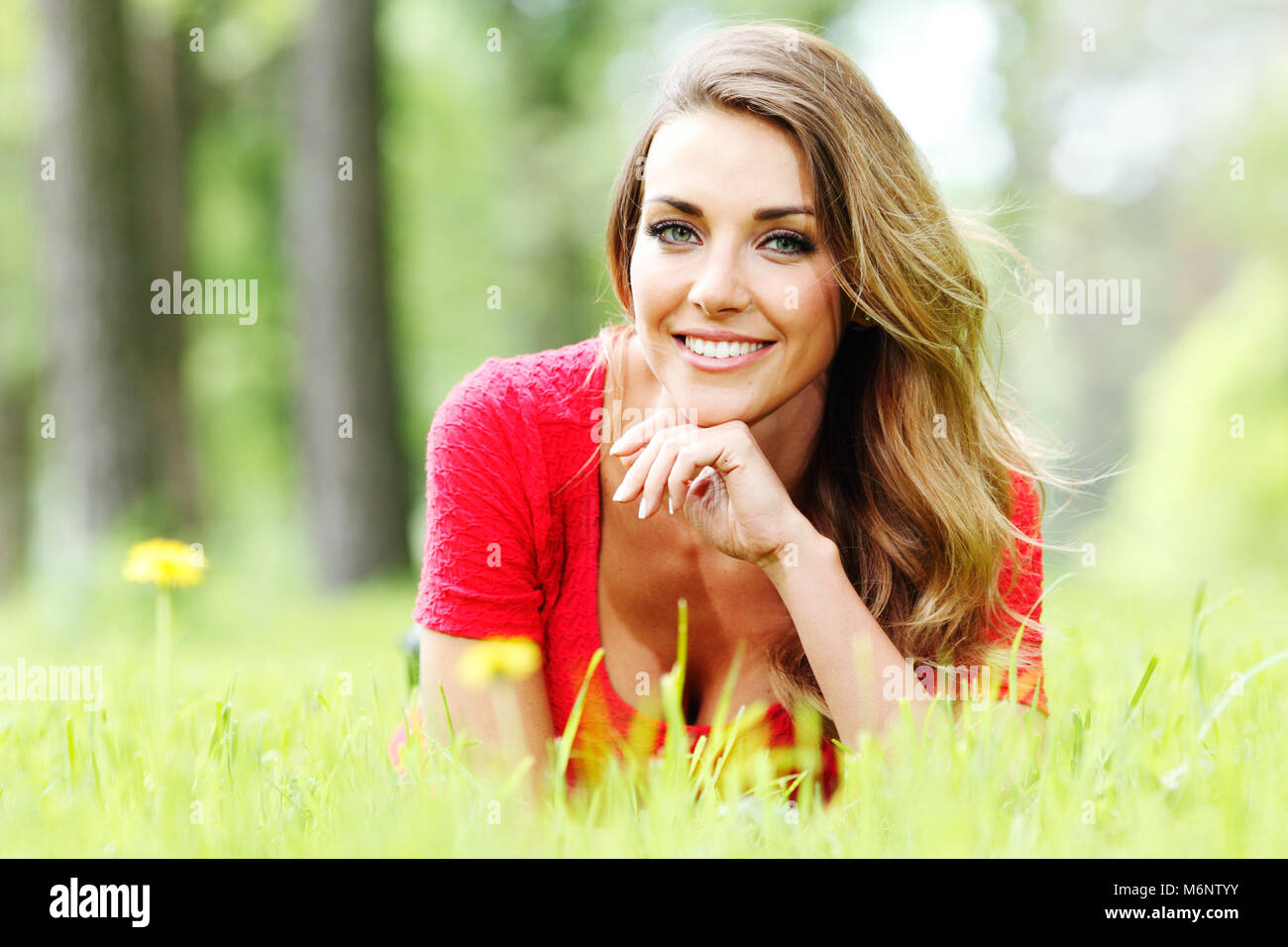 beautiful young woman in red dress lying on grass Stock Photo - Alamy