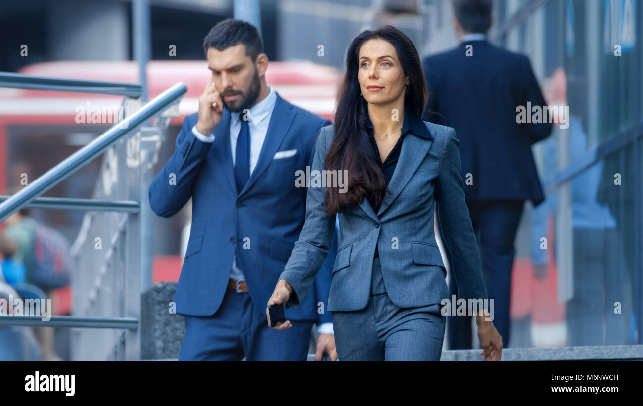 Male and Female Business People Walking Down the Street in the Business District. Stock Photo