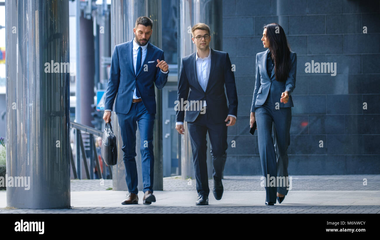 Male and Female Business People Walk and Discuss Business. They're all Working in Central Business District. Stock Photo