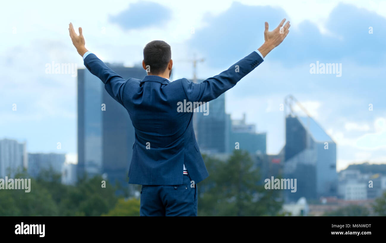 Happy Successful Business Man Raises His Hands, He Has His Business Victory. In The Background Big City with Skyscrapers. Stock Photo