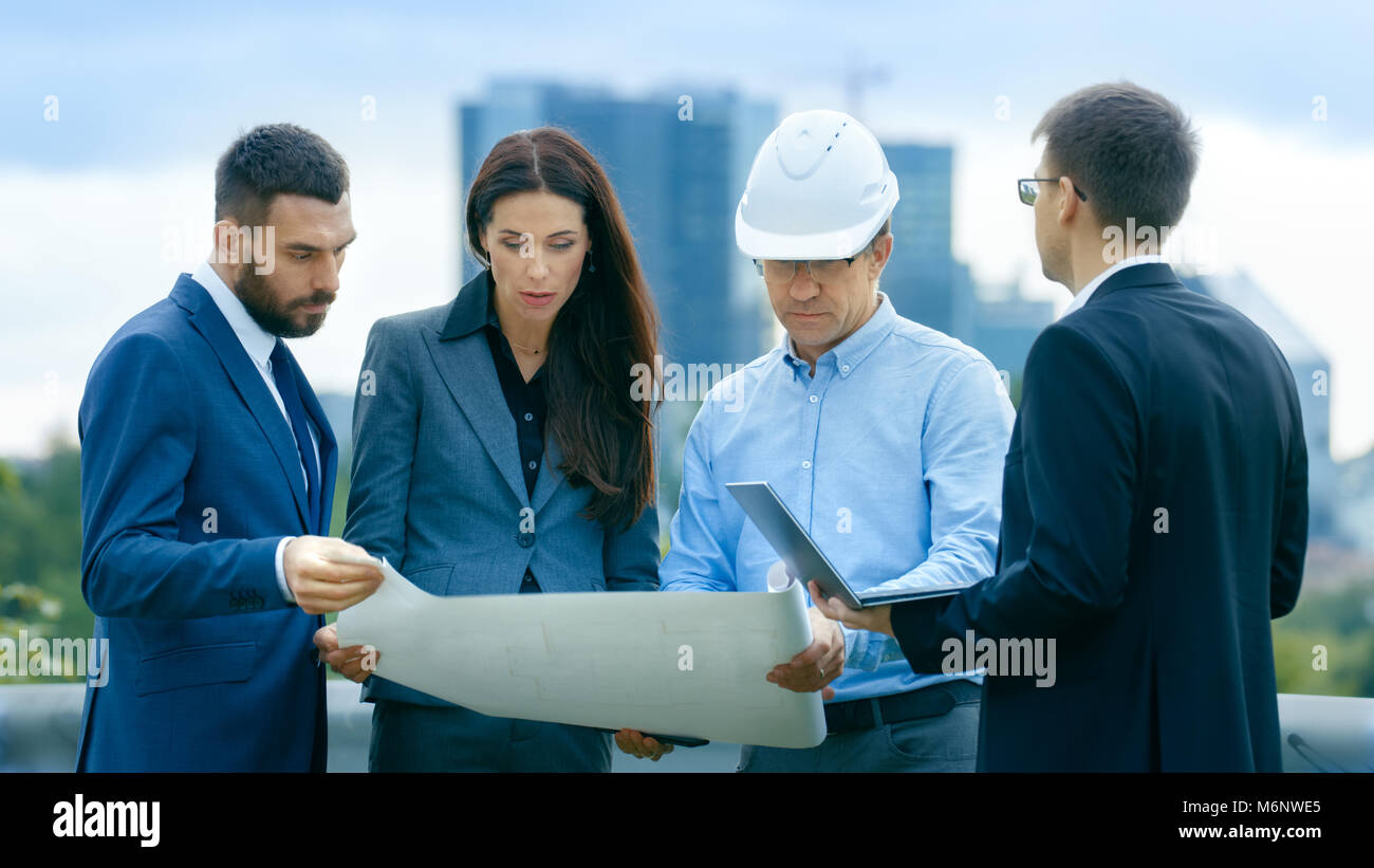 Team of Investors, Developers and Engineers Discuss Future of the Major Real Estate Project  with Major Contractor while Consulting Drafts and Plans.  Stock Photo