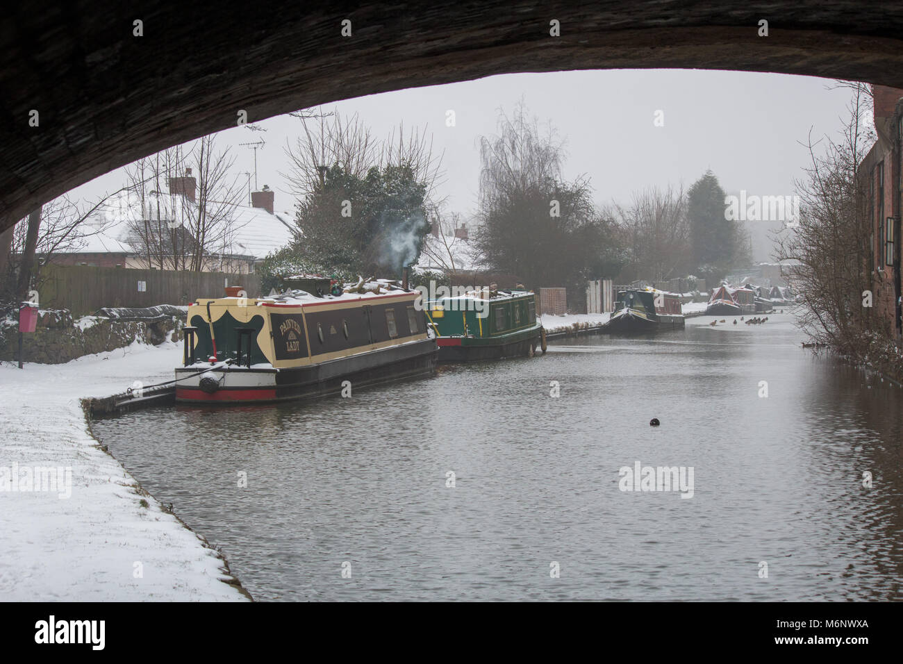 Canal boats, barges, narrow boats covered in snow on the Coventry canal, near Atherstone, Warwickshire Stock Photo