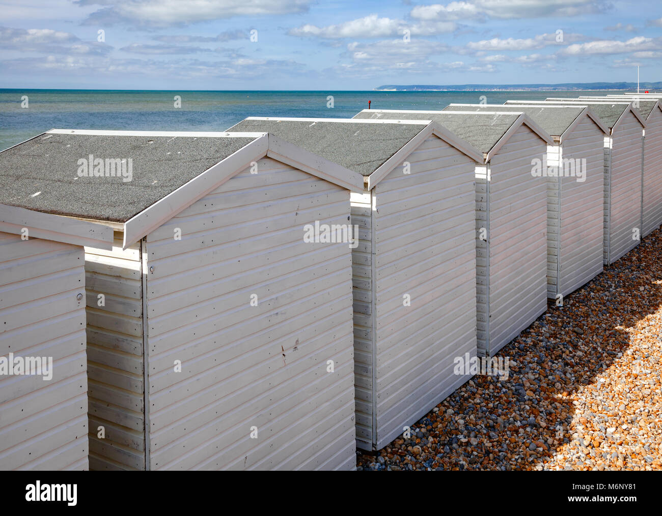 Row Of White Wooden Cabins On Shingle Beach At Popular Seaside