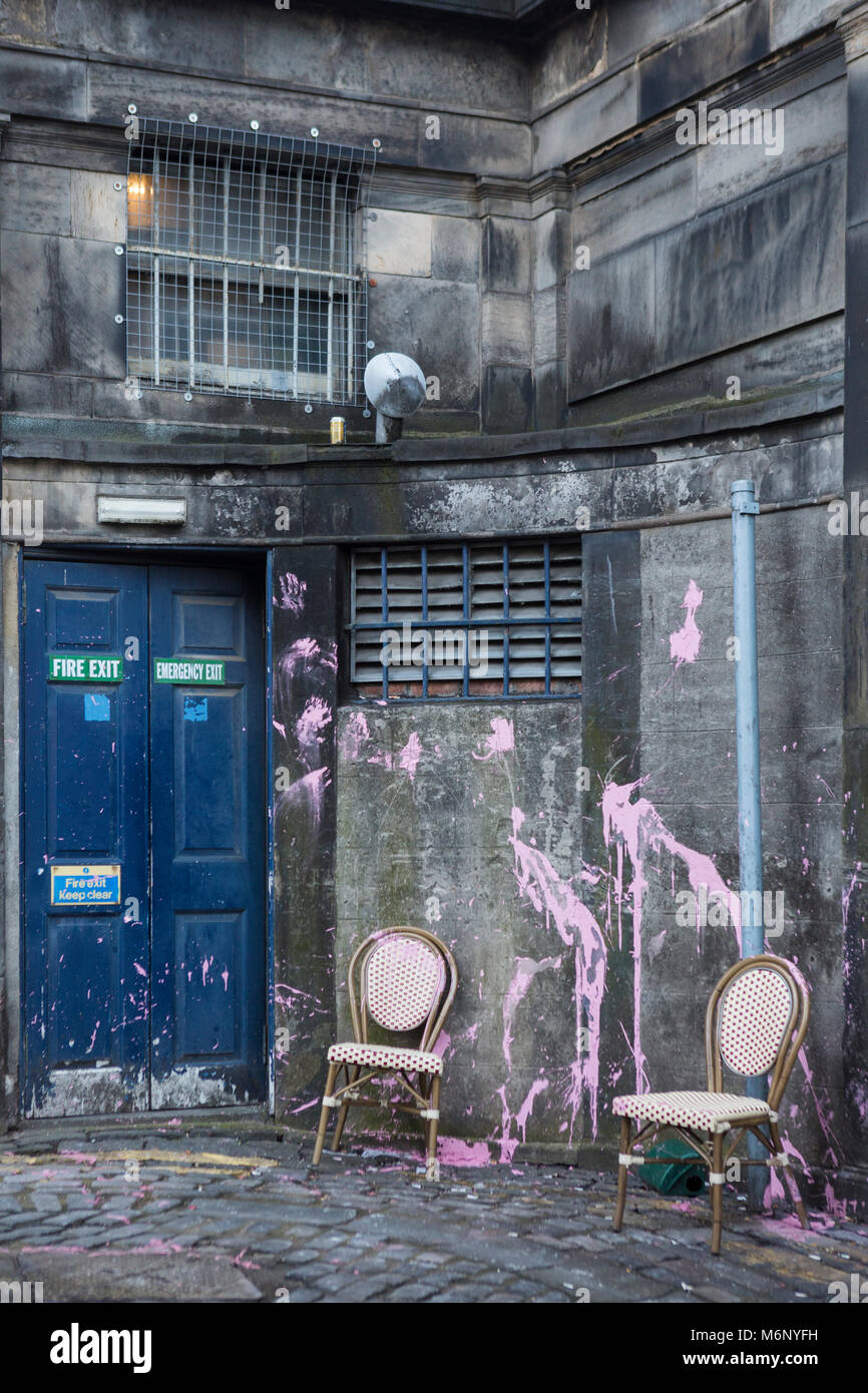 Pink paint splashed over a wall and two dining chairs, in a backstreet off Thistle Street, Edinburgh, Scotland. Stock Photo