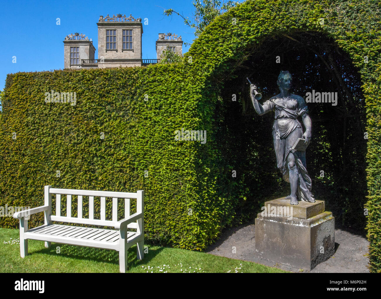 One of the four muse sculptures in an arched niche formed by a neatly clipped yew hedge in the gardens of Hardwick Hall in Derbyshire UK Stock Photo