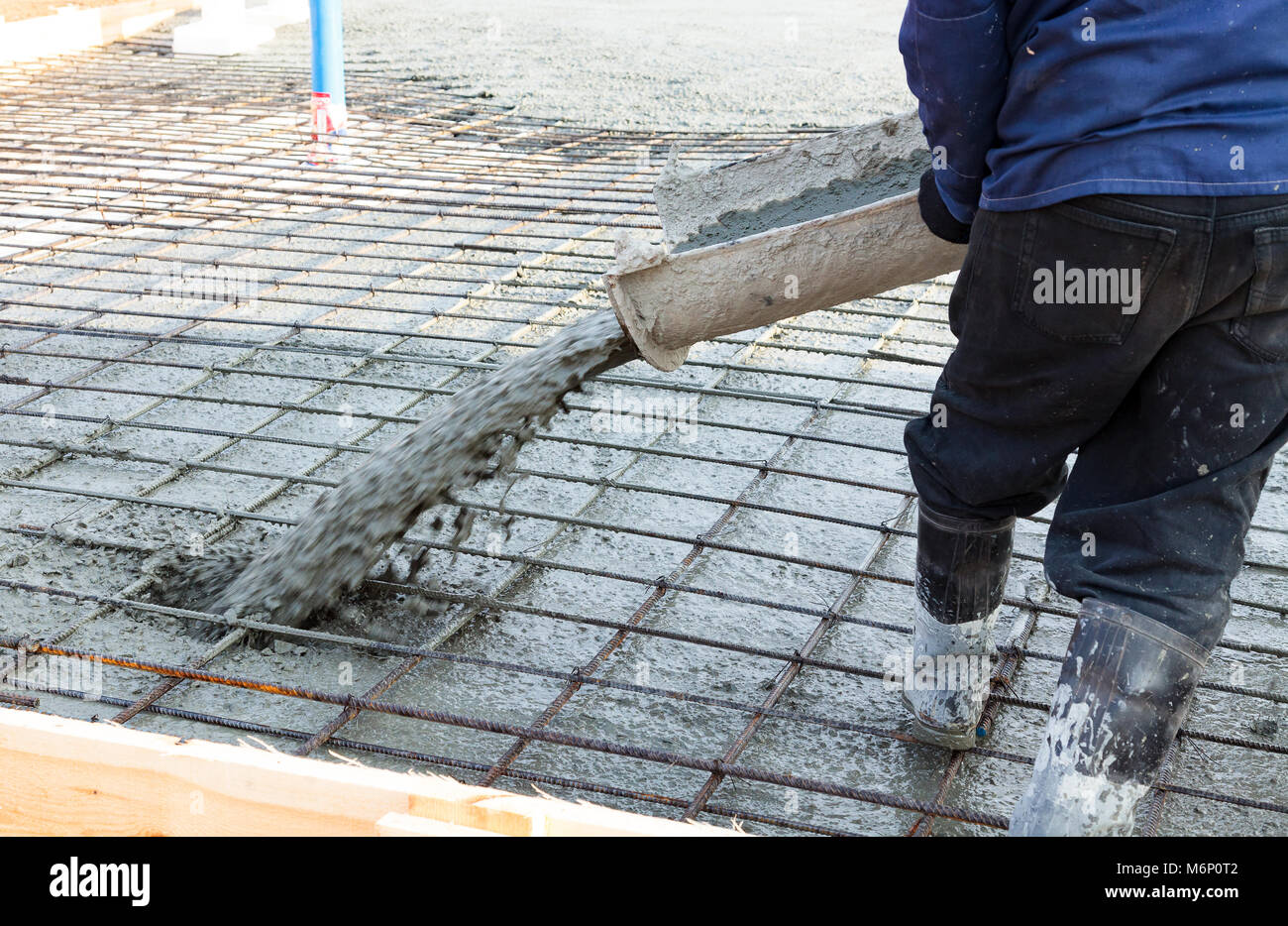 Closeup shot of concrete casting on reinforcing metal bars of floor in industrial construction site Stock Photo
