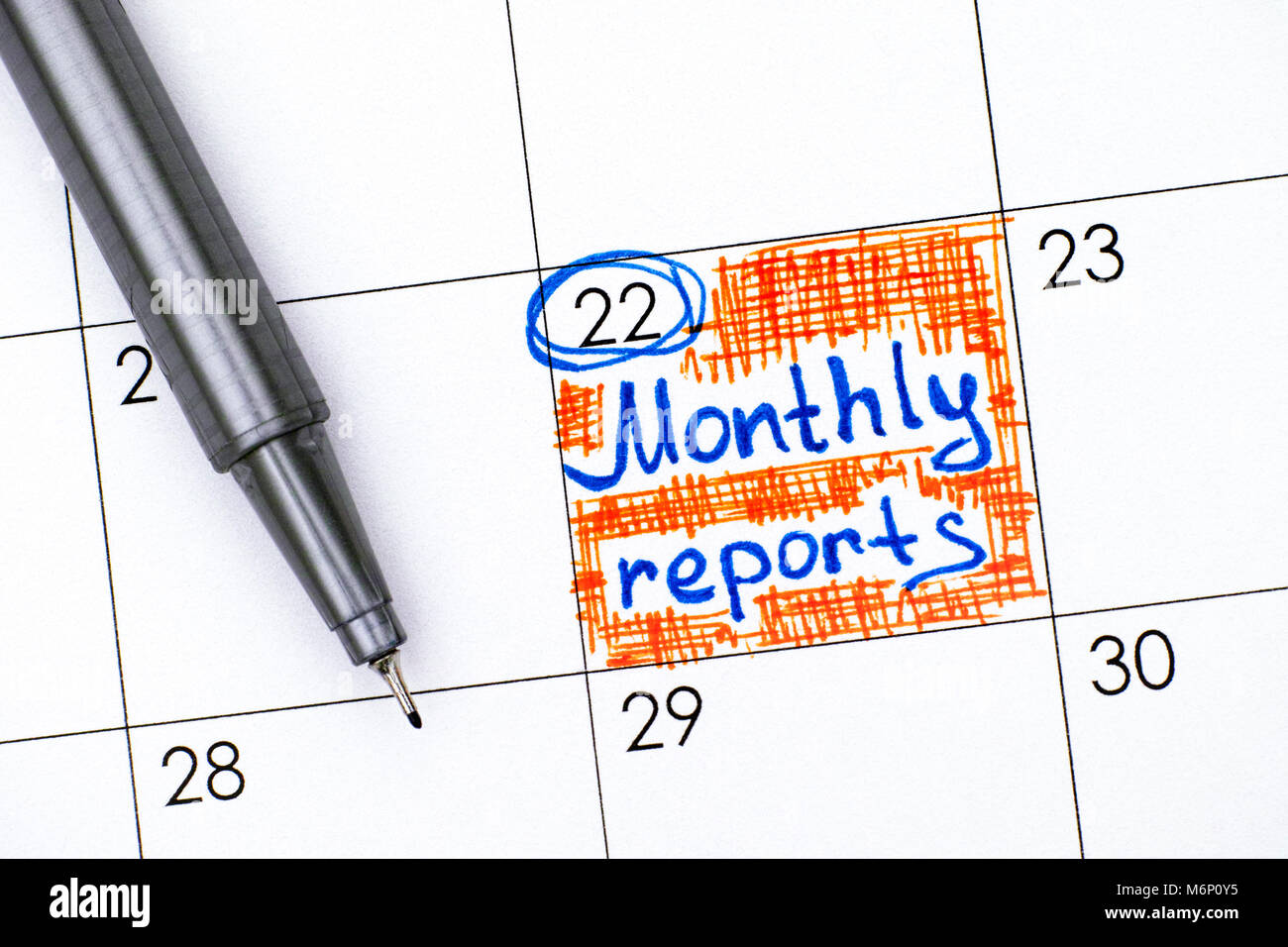Reminder Monthly Reports in calendar with pen. Close-up. Stock Photo