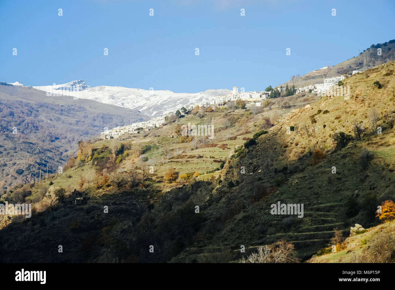 View of whitewashed Capileira village with snow-capped Sierra Nevada peaks in background in  Las Alpujarras, Granada province, Andalusia, Spain Stock Photo