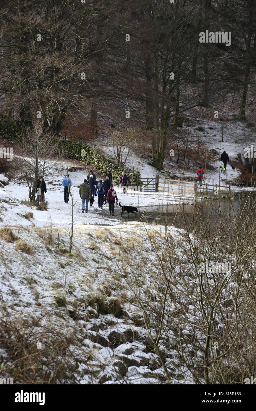 A large group of people walking in the snow at Grasmere Lake in the English Lake District Stock Photo