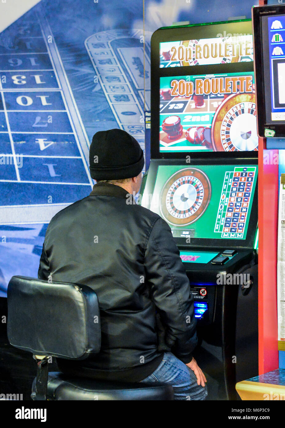 Mature man using fixed odds Roulette machine in Bookmakers. London, England, UK. Machine described as the Crack Cocaine of Gambling Stock Photo