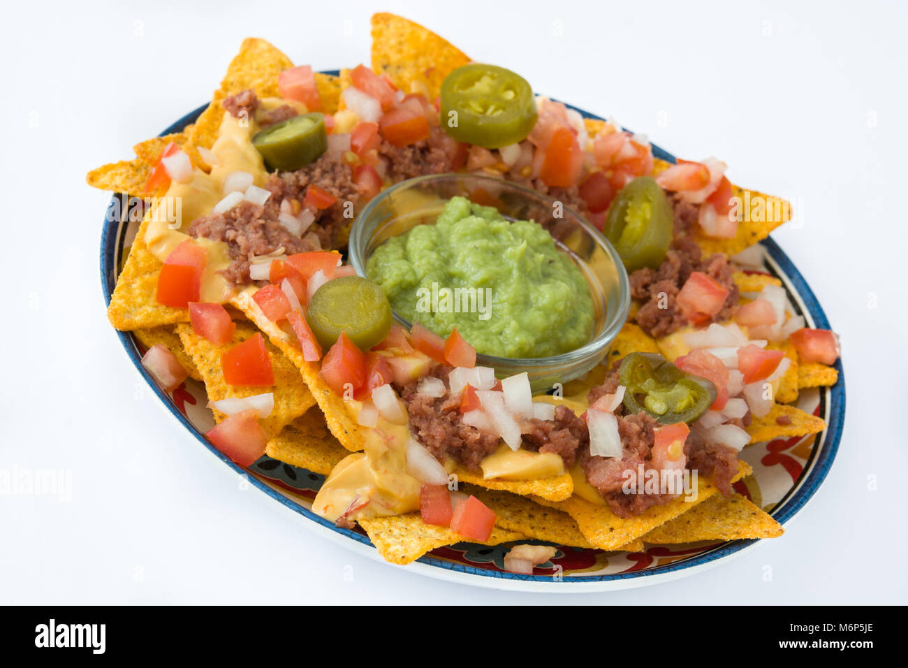 Mexican nachos with beef, guacamole, cheese sauce, peppers, tomato and ...