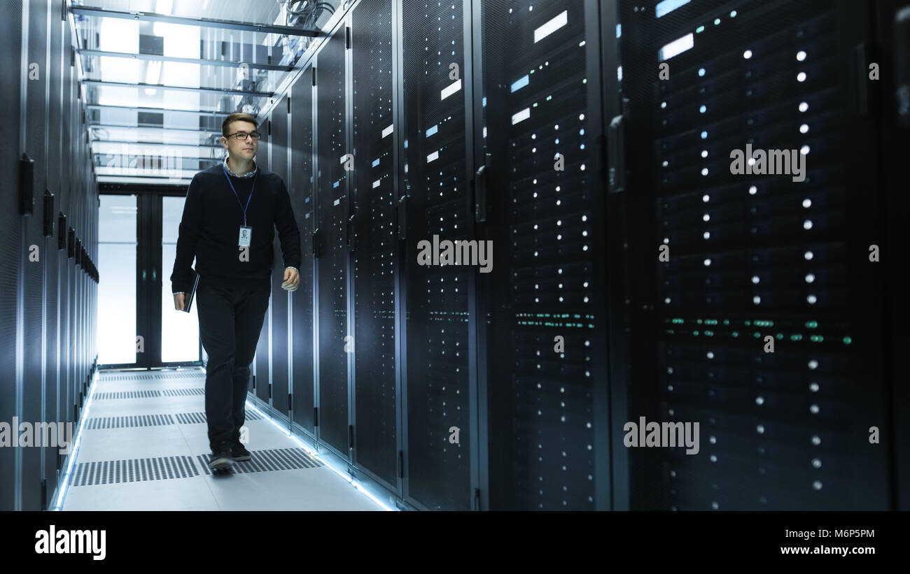IT Engineer Holding Notebook and Walking Through Data Center Full of ...