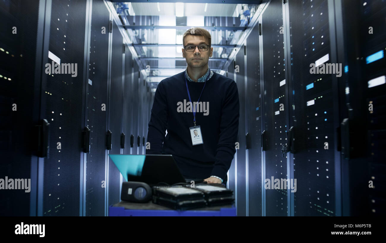 Shot of Server Engineer Pushing Crash Cart with Laptop, Hard Drives and