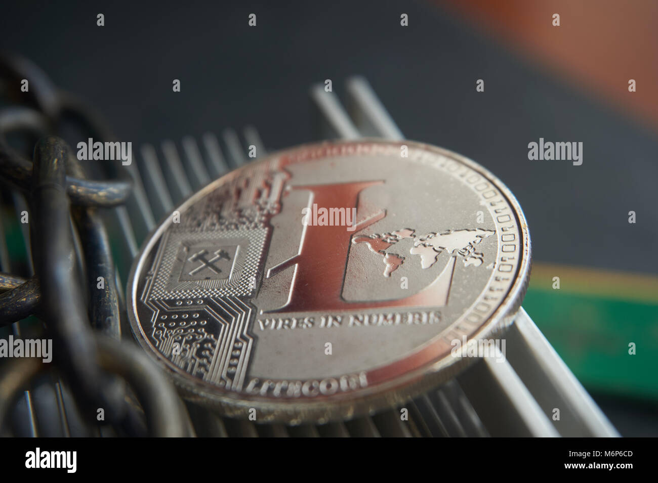 Silver litecoin coin  lying on the  aluminum computer cooler next to a copper chain. Cryptocurrency digging difficulty, blockchain and network concept Stock Photo