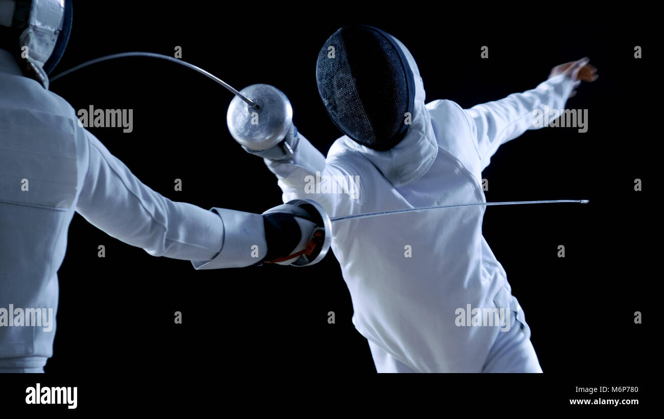 Two Professional Fencers Show Masterful Swordsmanship in their Foil Fight. They Attack, Defend, Leap and Thrust and Lunge. Stock Photo