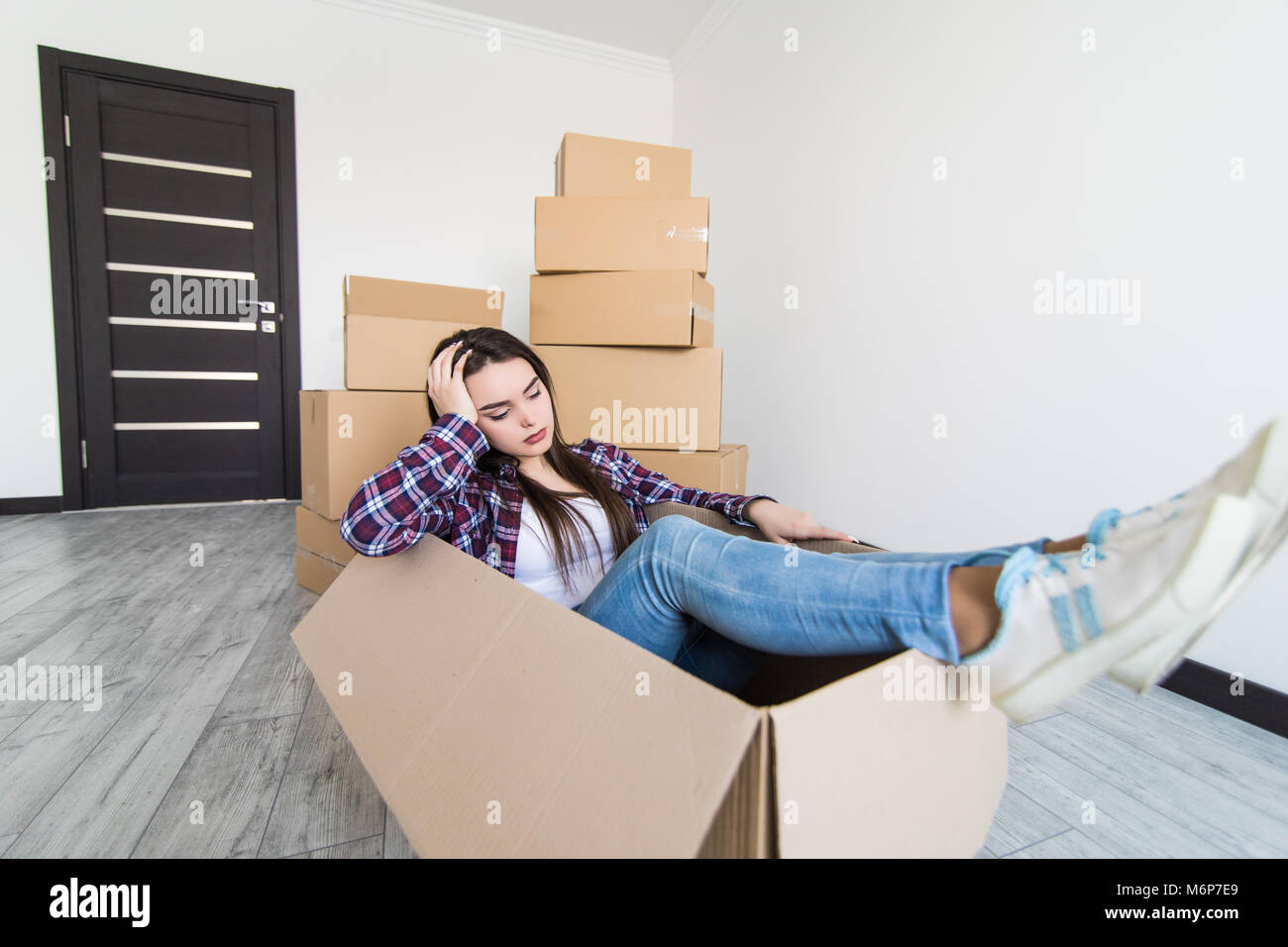 Sad and tired woman sitting in a cardboard box white moving in new ...